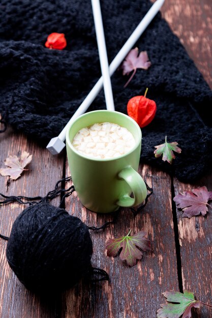 Kopje koffie of warme chocolademelk met marshmallow in de buurt van gebreide deken en breinaalden. Herfst concept.