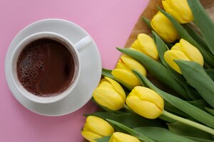 Kopje koffie onder gearrangeerd boeket gele tulpen bovenaanzicht