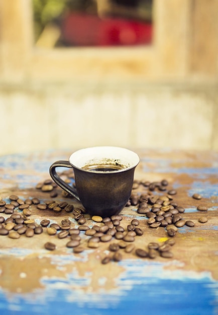 Kopje koffie onder koffiebonen op vintage houten tafel