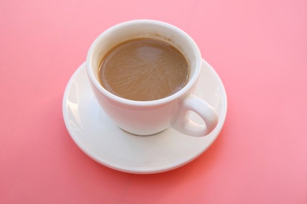 Kopje koffie op roze achtergrond.