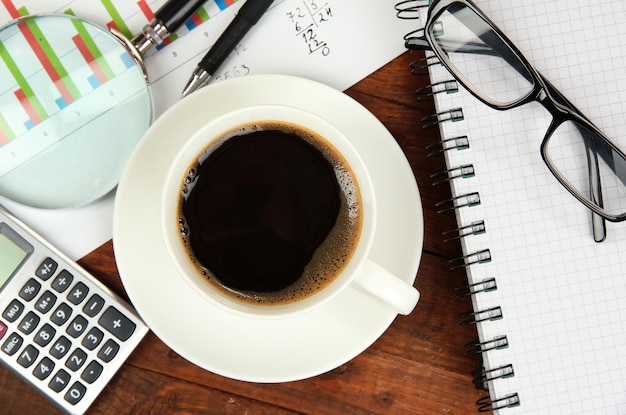 Kopje koffie op werktafel bedekt met documenten close-up