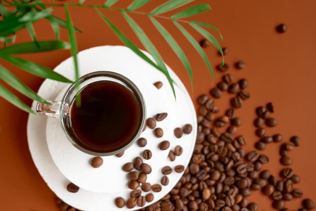 Kopje koffie op wit gipspodium op hete bruine achtergrond met koffiebonen en kaneel bovenaanzicht Cozzy morning concept
