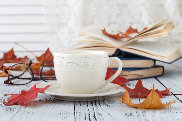 Kopje koffie, open boek en applique met bladeren op het houten oppervlak