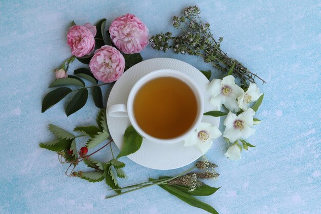 kopje kruidenthee met zomerbloemen op blauwe achtergrond