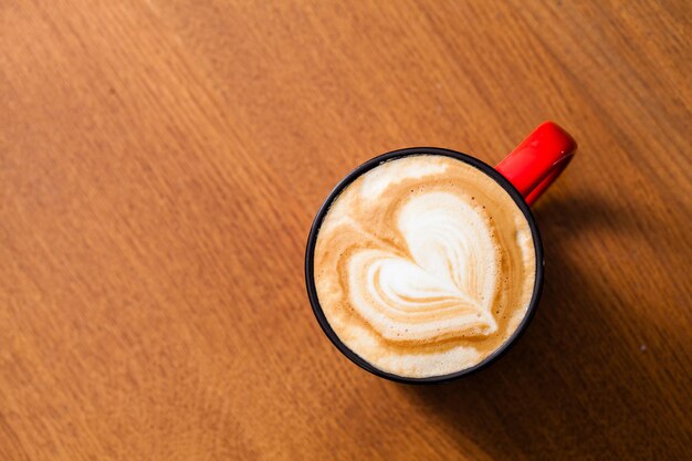 Kopje latte art koffie met hartvorm op houten tafel