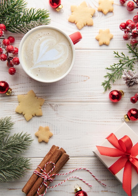 Kopje latte koffie en kerstversiering op een witte houten achtergrond