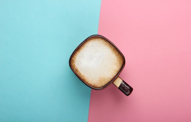 Kopje latte of cappuccino op roze blauwe pastelkleurachtergrond. Koffie met melk. Bovenaanzicht