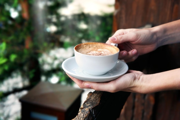 Kopje lekkere cappuccino met handen op straat achtergrond