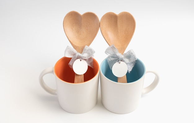 Kopje liefde, twee koffiekopjes met houten lepel in hartvorm op witte achtergrond