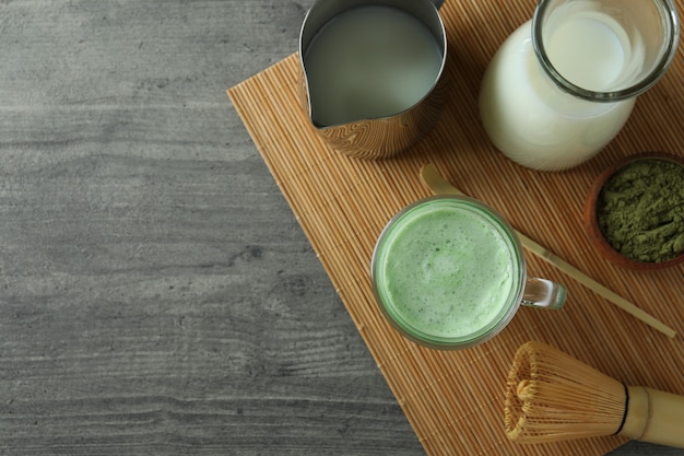 Kopje matcha latte en accessoires om te maken op een grijze getextureerde tafel