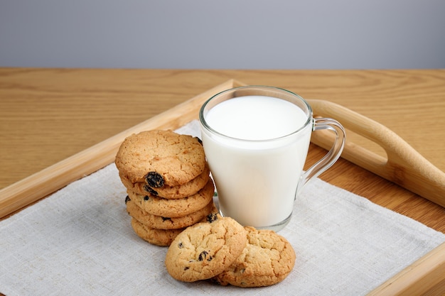 Kopje melk en koekjes met rozijnen op een houten dienblad