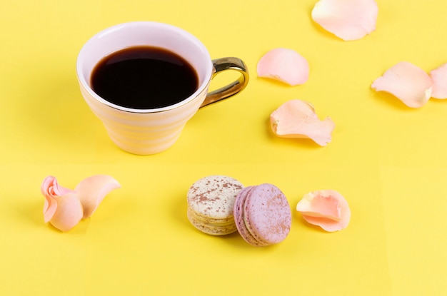 Kopje roze koffie met gekleurde macarons en rozenblaadjes