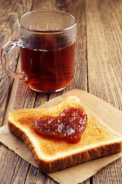 Kopje thee en brood met jam in de vorm van hart