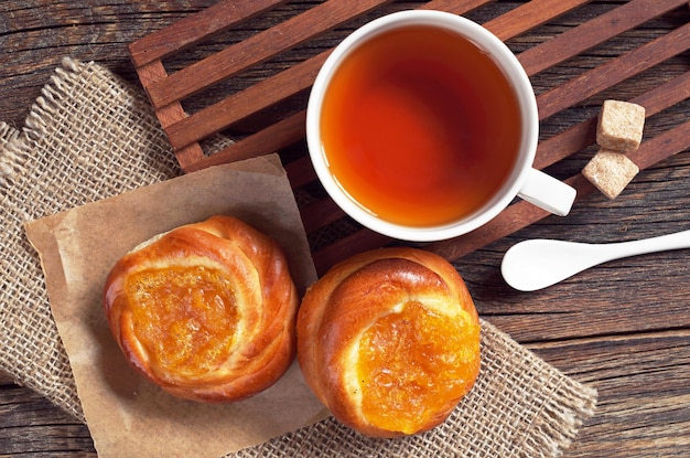 Kopje thee en broodje met jam op oude houten tafelblad weergave