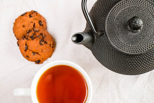 Kopje thee, ijzeren theepot en koekjes