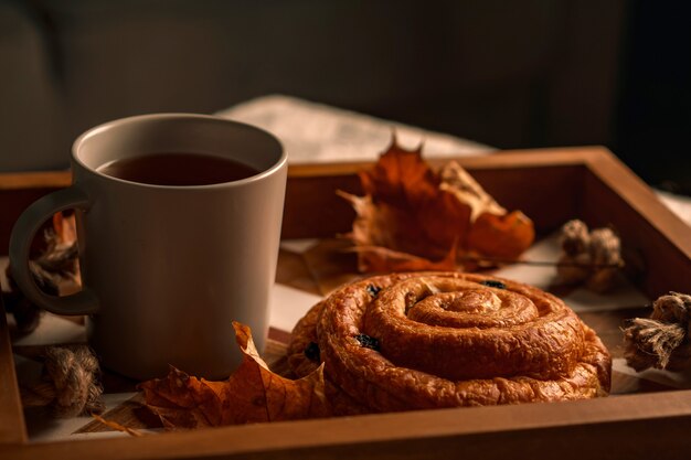 Kopje thee met gebak en herfstbladeren op dienblad