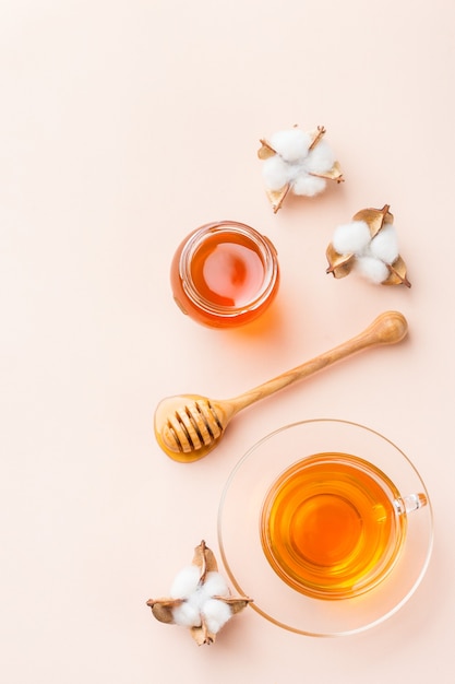 Kopje thee met honing op een trendy pastelroze, abrikoosachtergrond. Ruimte kopiëren, plat leggen