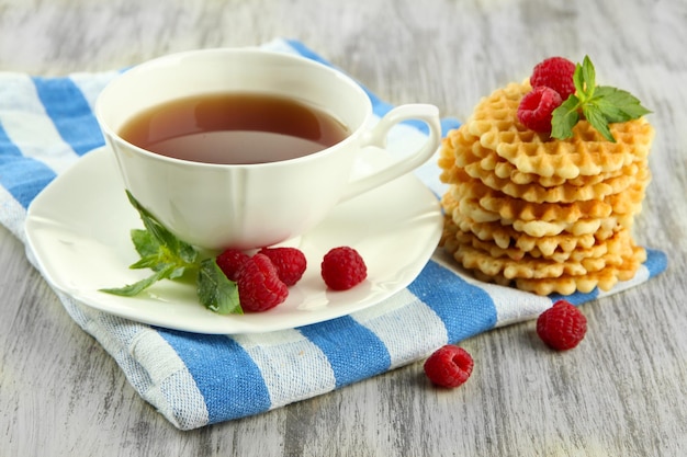 Kopje thee met koekjes en frambozen op tafel close-up