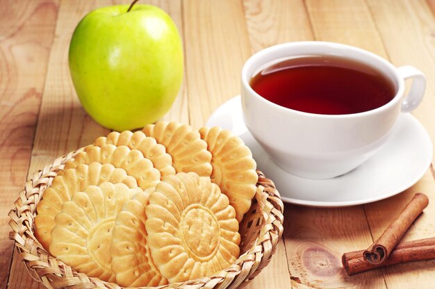 Kopje thee met koekjes en groene appel op houten tafel