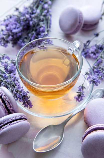 Kopje thee met lavendel-gearomatiseerd makarondessert op roze tegelsachtergrond