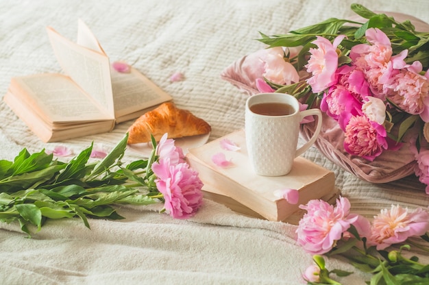 Kopje thee met Pions-bloemen en lentedecor op de boeken