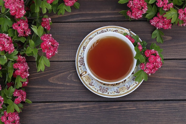 Kopje thee op bruine houten ondergrond met roze bloemen