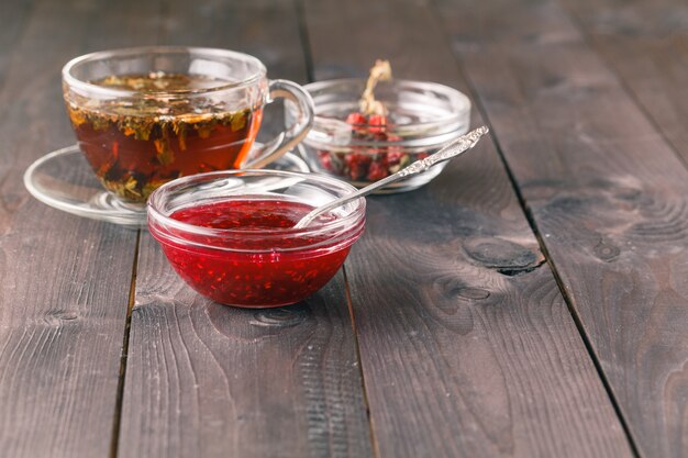 Kopje thee op houten tafel met frambozenjam