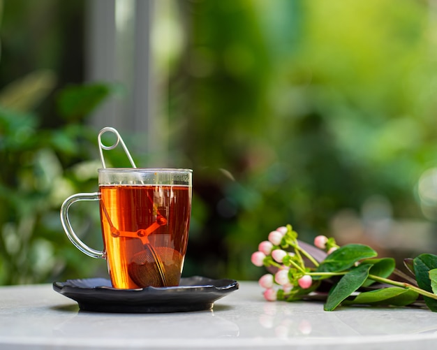 Kopje verse aromatische thee op tafel met natuur bloemen achtergrond