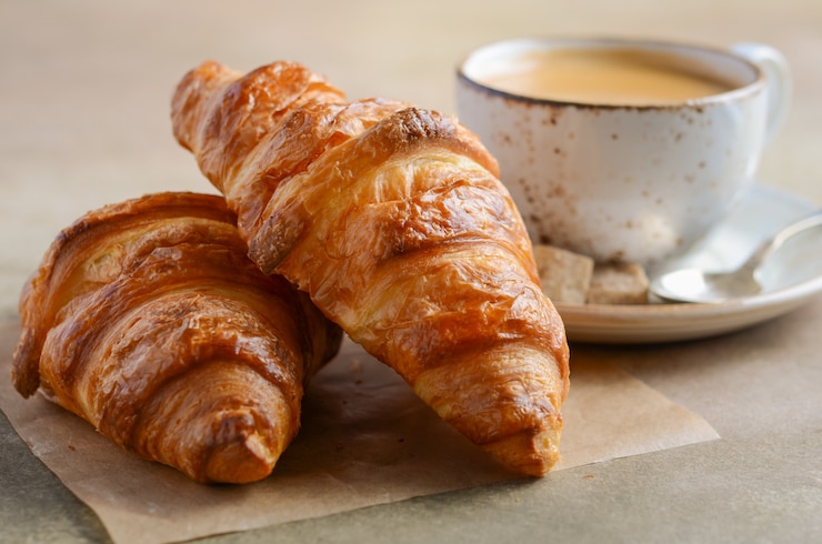 Foto kopje verse koffie met croissant op beton