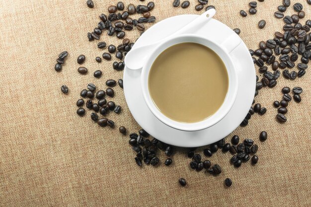 Kopje verse koffie met koffiebonen op jute warme kop op bruine achtergrond bovenaanzicht met vrije ruimte voor tekst