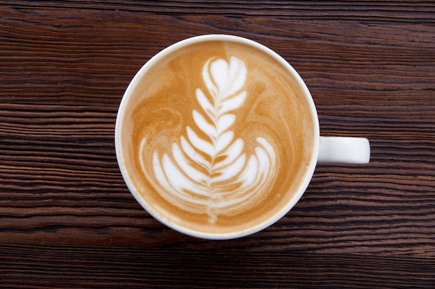 kopje warme cappuccino met patroon op houten achtergrond