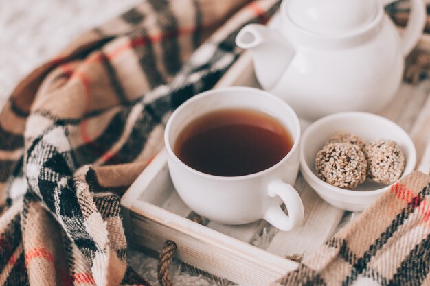 Kopje warme drank en theepot op een dienblad, kleding breien