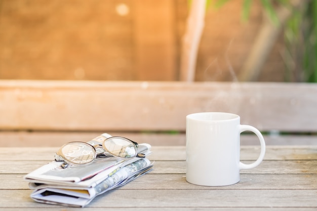 Kopje warme koffie, leesbril en krant o