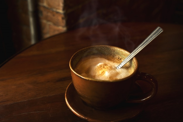 kopje warme koffie op tafel in cafe met ochtendlicht - vintage en donkere kleurstijl stijlen