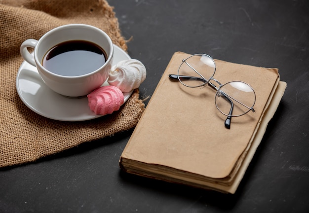 Kopje zwarte koffie en boek met een bril