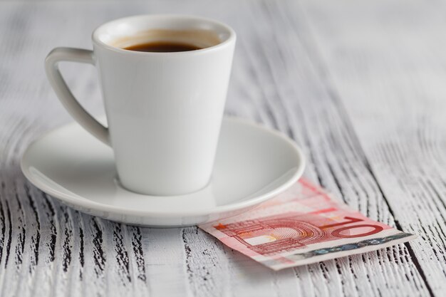 Kopje zwarte koffie en eurobankbiljetten