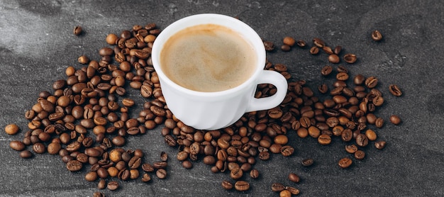 Kopje zwarte koffie met bonen op houten tafel