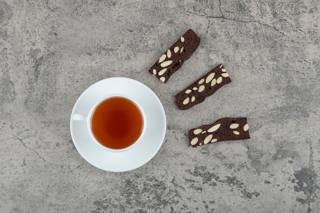 Kopje zwarte thee met cacaocrackers op stenen tafel.