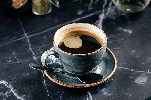 Kopje zwarte vers gezette koffie op de donkere marmeren tafel