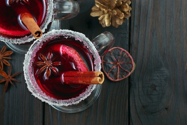 Kopjes glühwein, kruiden en droge citrusvruchten op een houten tafelblad bekijken verwarmende kerstdrank close-up kopie ruimte