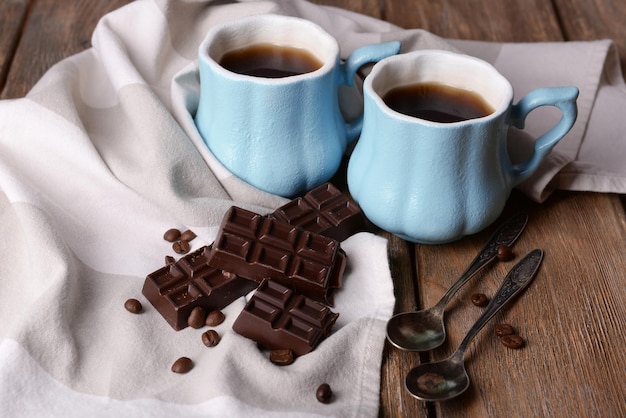 Kopjes koffie met chocolade en servet op houten tafel