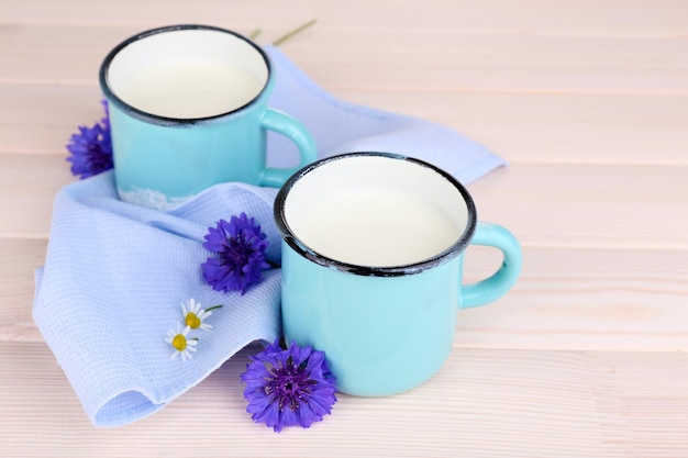 Kopjes melk en korenbloemen op houten tafel