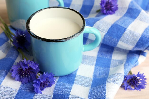 Kopjes melk en korenbloemen op houten tafel