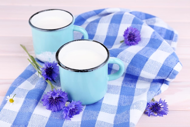 Kopjes melk en maïsbloemen op een houten tafel.
