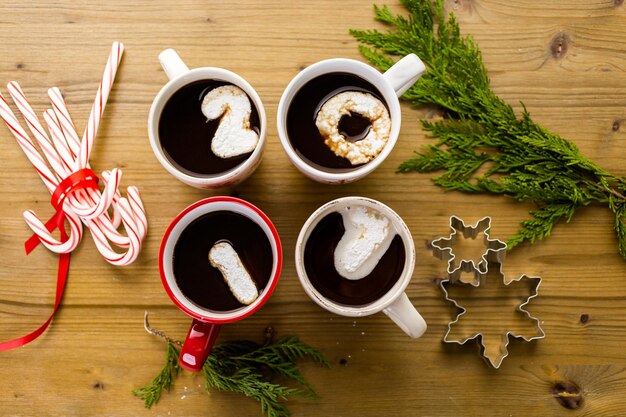 Kopjes met warme chocolademelk gegarneerd met witte marshmallows op houten tafel.