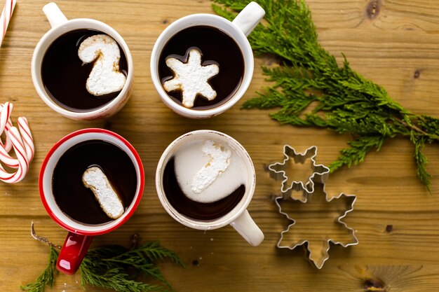 Kopjes met warme chocolademelk gegarneerd met witte marshmallows op houten tafel.