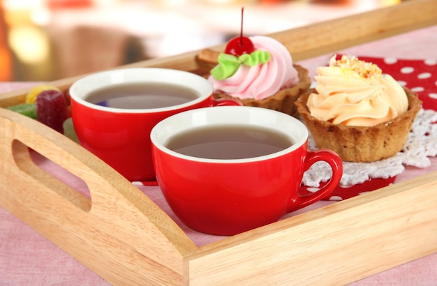 Kopjes thee met gebak op houten dienblad op tafel in café