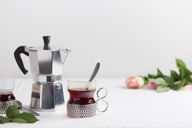 Kopjes verse koffie en koffiezetapparaat op witte tafel