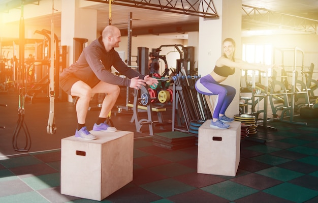 Koppel functionele training. Fitness man en vrouw springen op de houten kisten in de sportschool