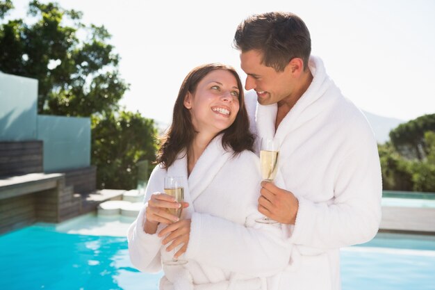 Koppel met champagne fluiten bij het zwembad